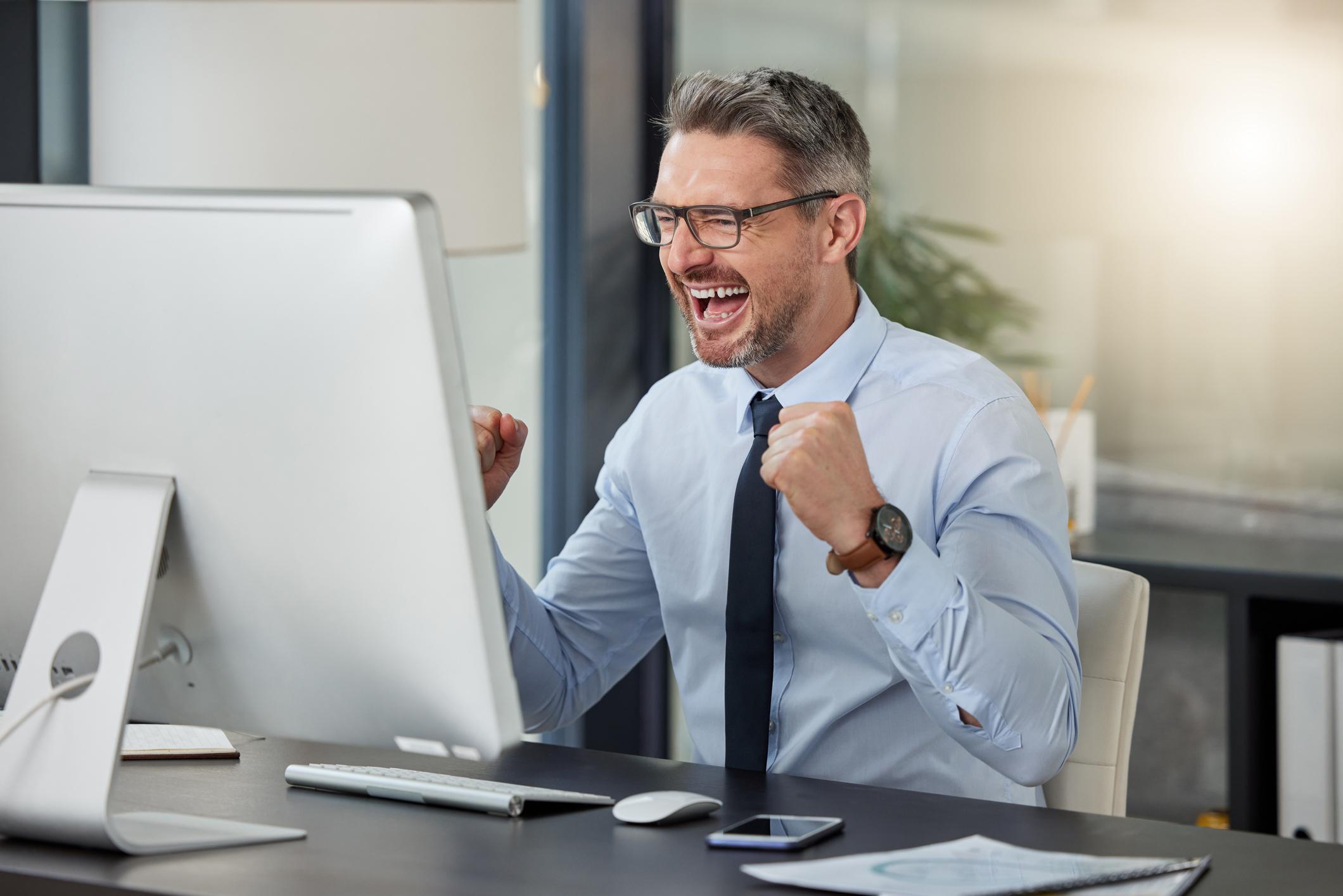 Picture shows a mature gentleman at an office computer celebrating something he's just learned.